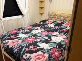 A bedroom with a floral bedspread and shelves at Gannet 19 (G19) Bridlington