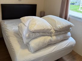 A bed with a stack of pillows and a duvet at Dunlin dell 45 (D45) Bridlington