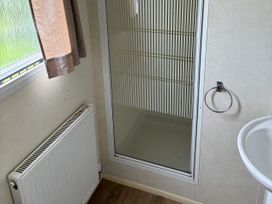 A bathroom with a shower, sink and radiator at Dunlin dell 45 (D45) Bridlington