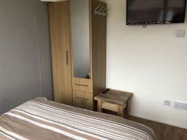 A bedroom with a mirror cabinet and television at Chalet in Bridlington