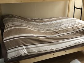A bed with striped bedding and pillow at Chalet in Bridlington
