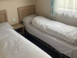 A bedroom with two single beds and a bedside table at Skegness Holiday Park in Skegness