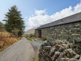 A rural scene with a stone building along a road at Newlands Fell Cottage in Newlands near Keswick