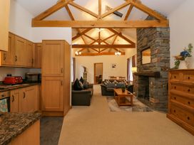 A kitchen with wooden cabinets and a living room with a sofa at Newlands Fell Cottage in Newlands near Keswick
