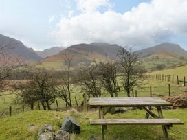 A table near a fence with trees and mountains at Newlands Fell Cottage Newlands near Keswick