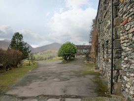 An outdoor view of a stone building with trees and mountains at Newlands Fell Cottage, Newlands near Keswick