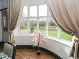 A dining room with a curvilinear window and an artificial plant at Herdwick Croft in Bassenthwaite