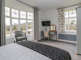A bedroom with a bed, desk, and windows at Herdwick Croft in Bassenthwaite