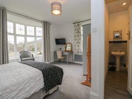 A bedroom with a bed, desk, chair, and a bathroom at Herdwick Croft in Bassenthwaite