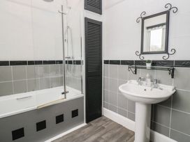A bathroom featuring a bathtub with a shower and a sink at Herdwick Croft in Bassenthwaite