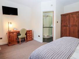 A bedroom with a bed, wardrobe, desk, chair and shower at Birkbank Farm in Cockermouth