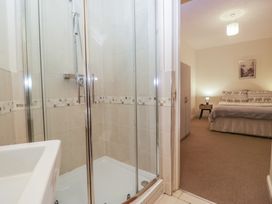 A bathroom with a shower and sink adjoining a bedroom at Birkbank Farm in Cockermouth