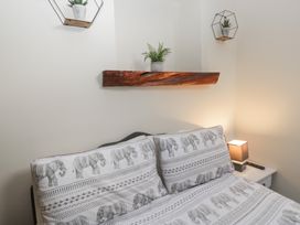 A bedroom with a bed and decorative plant shelf at Birkbank Farm in Cockermouth