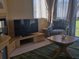 A living room with a television and a chair at Red Lion Caravan Park in Arbroath