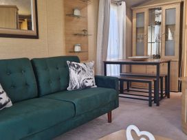 A living room with a green sofa and a dining table at Red Lion Caravan Park Arbroath