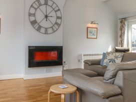 A living room with a clock and electric fireplace at Flat 1