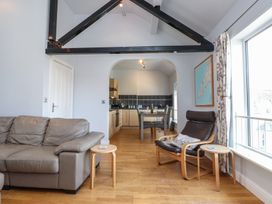A living room with a sofa and dining area at Flat 1