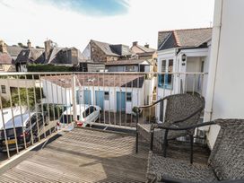 A balcony with chairs overlooking buildings and parked cars at Flat 1