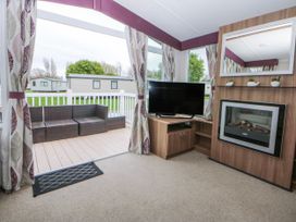 A living room with a sofa and television at 49 Cader Idris, Hafan-Y-Mor Holiday Park Pwllheli