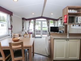 A living room with a dining area and sofa at 49 Cader Idris, Hafan-Y-Mor Holiday Park Pwllheli