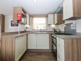 A kitchen with a sink and stove at 49 Cader Idris, Hafan-Y-Mor Holiday Park Pwllheli