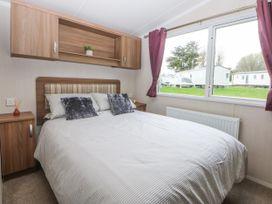 A bedroom with a double bed and a window at 49 Cader Idris, Hafan-Y-Mor Holiday Park Pwllheli