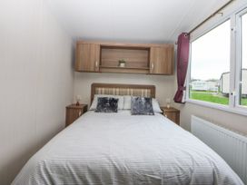 A bedroom with a bed and window at 49 Cader Idris, Hafan-Y-Mor Holiday Park, Pwllheli