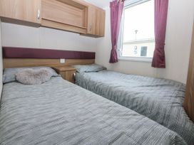 A bedroom with two beds and a window at 49 Cader Idris, Hafan-Y-Mor Holiday Park, Pwllheli