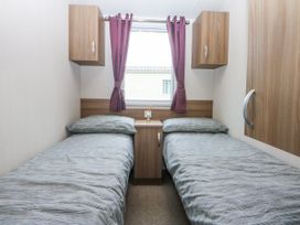 A bedroom with two single beds and a window at 49 Cader Idris, Hafan-Y-Mor Holiday Park, Pwllheli