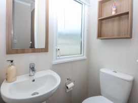 A bathroom with a sink, toilet, and a window at 49 Cader Idris, Hafan-Y-Mor Holiday Park Pwllheli