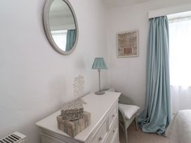A bedroom with a dresser, lamp, and window at Mariners Cottage in Bideford