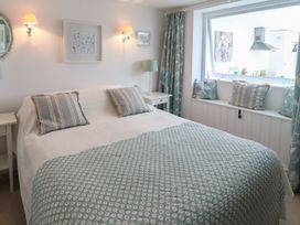 A bedroom with a bed and light fixtures at Mariners Cottage in Bideford