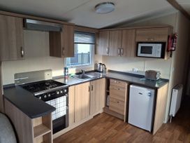 A kitchen with cabinets, sink, gas stove, microwave, and refrigerator at Caravan