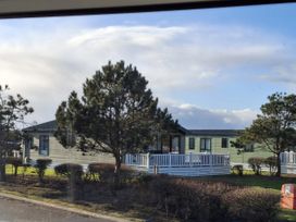 A mobile home with trees and a patio area at Caravan
