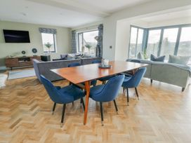 A living room with a dining area and large windows at Pengarnedd Amlwch