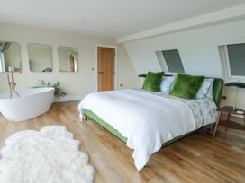 A bedroom with a bed, bathtub, and mirrors at Pengarnedd in Amlwch