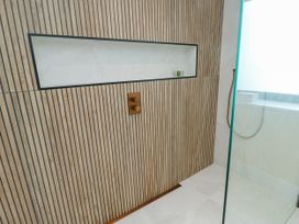 A shower area with wood paneling and shower controls at Pengarnedd in Amlwch