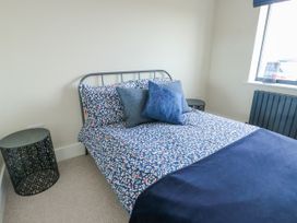 A bedroom with a bed, cushions, bedside table, and a window at Pengarnedd in Amlwch
