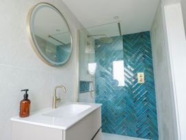 A bathroom with a shower, sink and mirror at Pengarnedd in Amlwch