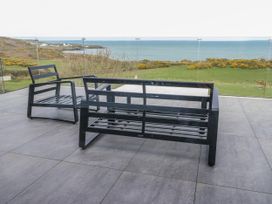 A patio with chairs and a table overlooking the sea at Pengarnedd Amlwch