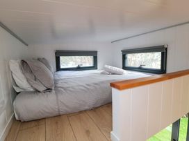 A loft space with a bed and windows at The Tiny Home