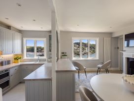 A kitchen with cabinets, a countertop, sink, dining table and chairs at Bell Cottage in Dartmouth