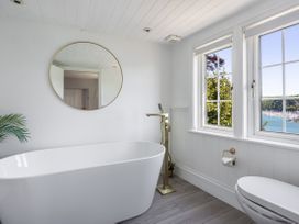 A bathroom with a bathtub, toilet, and windows at Bell Cottage in Dartmouth