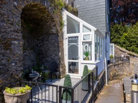 An outdoor patio with a stone wall and seating at Bell Cottage Dartmouth