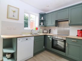 A kitchen with green cabinets, sink, oven and kettle at Meadow View in Kinmel Bay