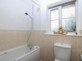 A bathroom with a bathtub, toilet, and a window at Meadow View in Kinmel Bay
