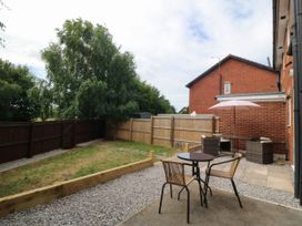 A garden with a table, chairs, and an umbrella at Meadow View in Kinmel Bay