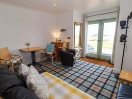 A living room with a sofa, chairs, and a table at Ty Mor in Newport, Pembrokeshire