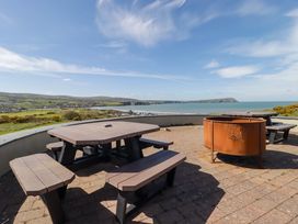 An outdoor area with a table, benches, and a fire pit overlooking the sea at Ty Mor in Newport, Pembrokeshire