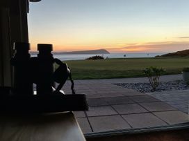 A view of a golf course and ocean with binoculars at Ty Mor in Newport, Pembrokeshire